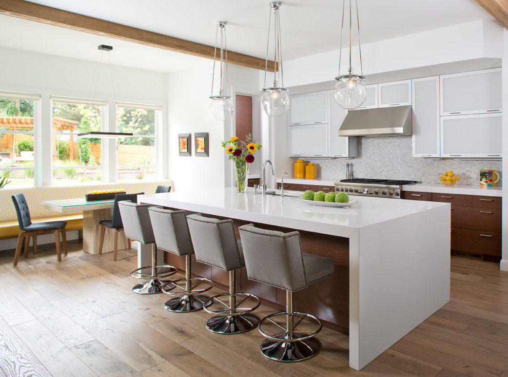 This is an example of a transitional eat-in kitchen in Denver with an undermount sink, white cabinets, grey splashback, stainless steel appliances, light hardwood floors, with island and beige floor.