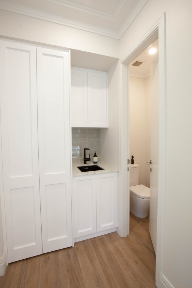 This is an example of a small beach style single-wall utility room in Sydney with a drop-in sink, shaker cabinets, white cabinets, quartz benchtops, green splashback, ceramic splashback, white walls, porcelain floors, multi-coloured floor, multi-coloured benchtop and recessed.