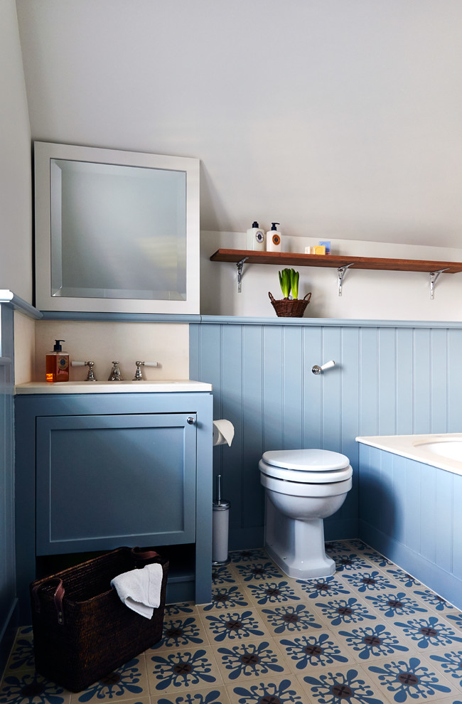 Design ideas for a small transitional bathroom in London with shaker cabinets, blue cabinets, a one-piece toilet and blue walls.