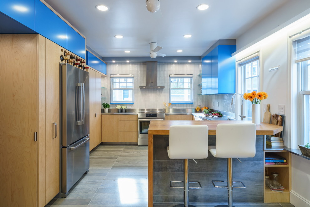 Inspiration for a mid-sized contemporary u-shaped eat-in kitchen in Boston with with island, an integrated sink, flat-panel cabinets, blue cabinets, wood benchtops, white splashback, ceramic splashback, stainless steel appliances and porcelain floors.