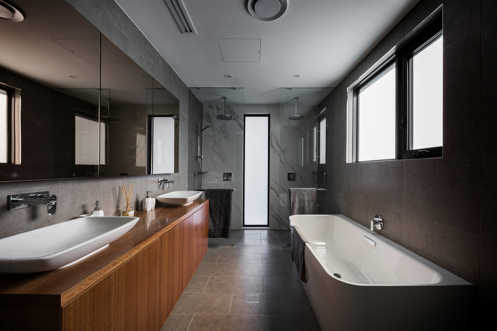 This is an example of a mid-sized contemporary bathroom in Canberra - Queanbeyan with flat-panel cabinets, medium wood cabinets, black tile, porcelain tile, black walls, porcelain floors, a vessel sink, wood benchtops, black floor, an open shower, a freestanding tub, a double shower and brown benchtops.
