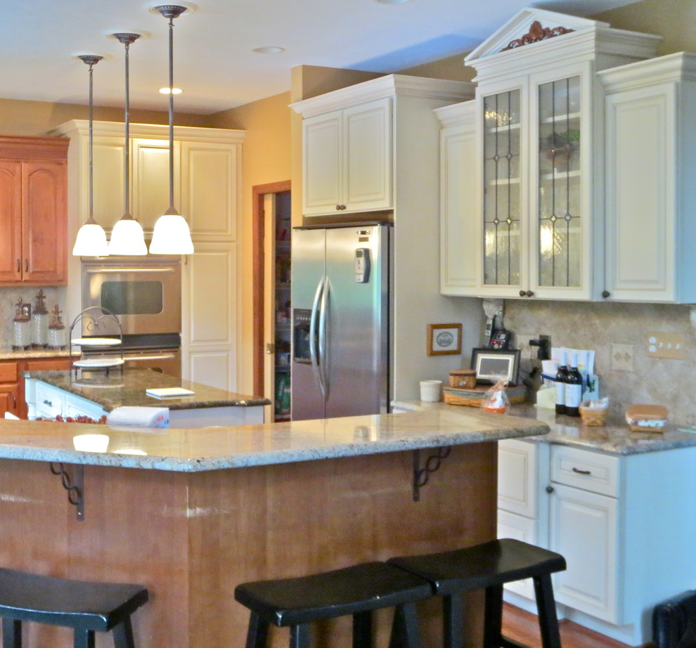 Inspiration for a large timeless u-shaped medium tone wood floor enclosed kitchen remodel with raised-panel cabinets, white cabinets, granite countertops, beige backsplash, stainless steel appliances, yellow walls and an island