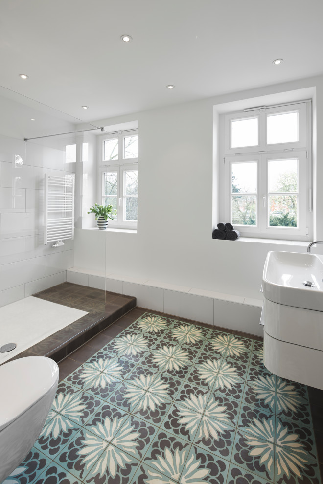 Inspiration for a traditional 3/4 bathroom in Essen with flat-panel cabinets, white cabinets, an open shower, a wall-mount toilet, white tile, white walls, cement tiles, a shower seat, a single vanity and a built-in vanity.