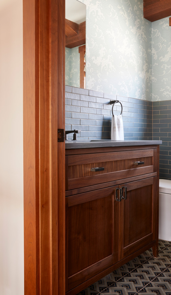 Design ideas for an arts and crafts bathroom in New York with raised-panel cabinets, medium wood cabinets, blue tile, porcelain tile, blue walls, cement tiles, soapstone benchtops, multi-coloured floor, grey benchtops, a single vanity, timber and wallpaper.