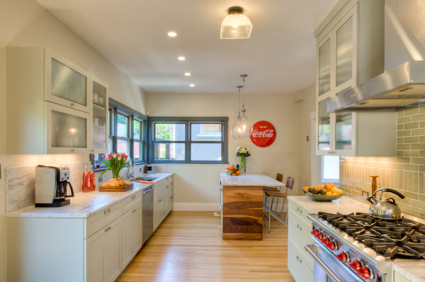 Photo of a large contemporary galley eat-in kitchen in San Francisco with a double-bowl sink, shaker cabinets, white cabinets, granite benchtops, white splashback, stone slab splashback, stainless steel appliances, light hardwood floors and with island.