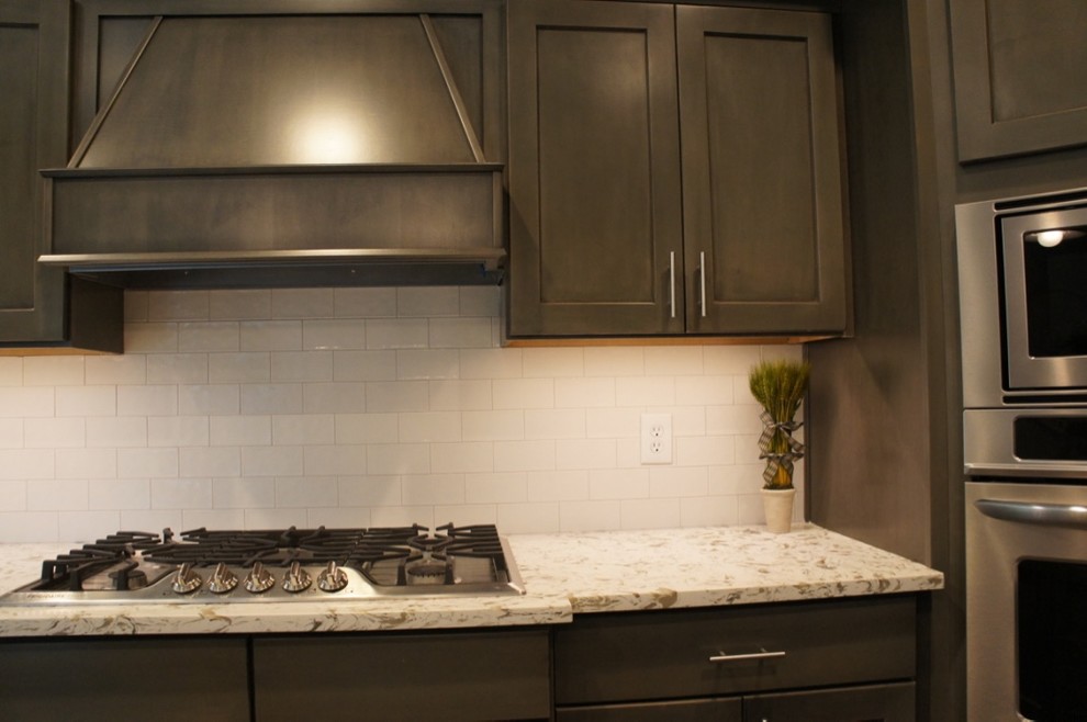 Example of a transitional u-shaped eat-in kitchen design with flat-panel cabinets, white backsplash, stainless steel appliances and an island