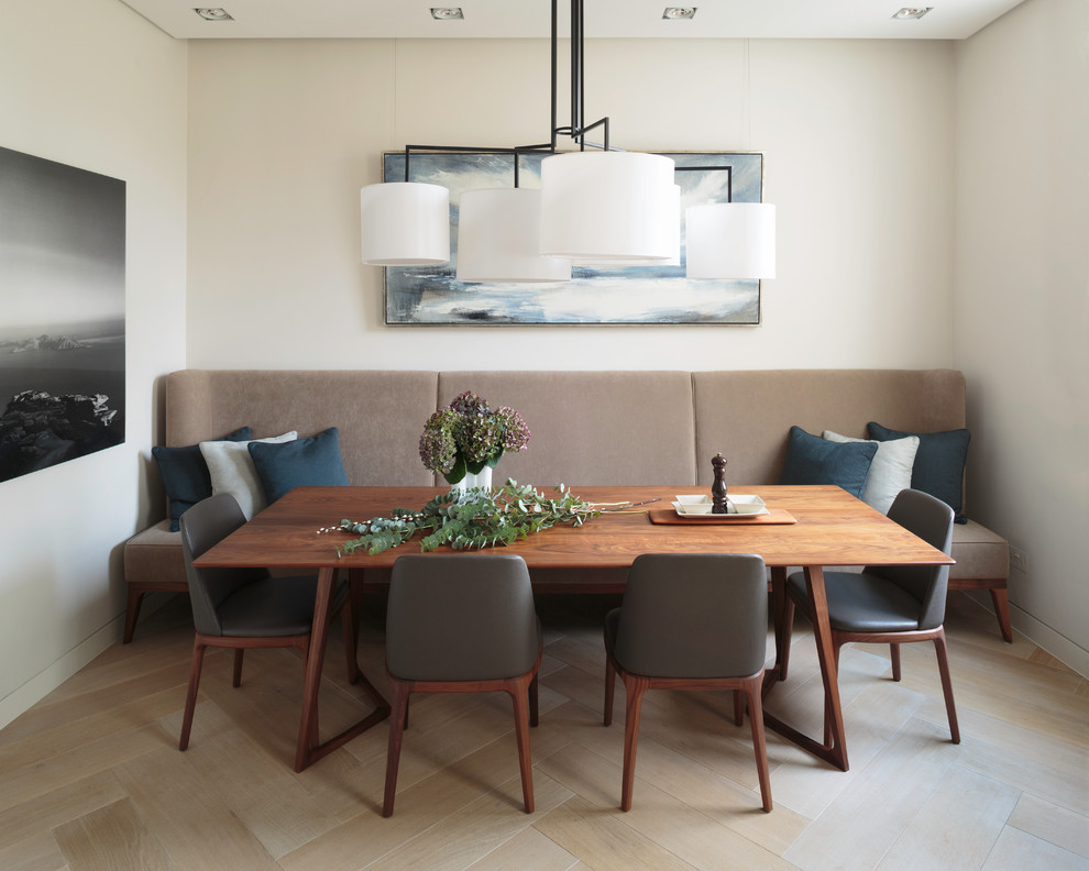 This is an example of a midcentury dining room in London with light hardwood floors and white walls.
