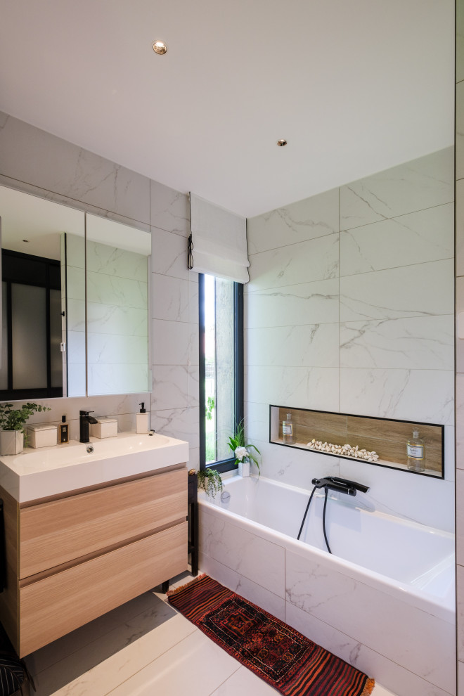 Photo of a transitional bathroom in Bordeaux with an undermount tub, gray tile, marble, marble floors, a trough sink, solid surface benchtops, grey floor, white benchtops and a niche.