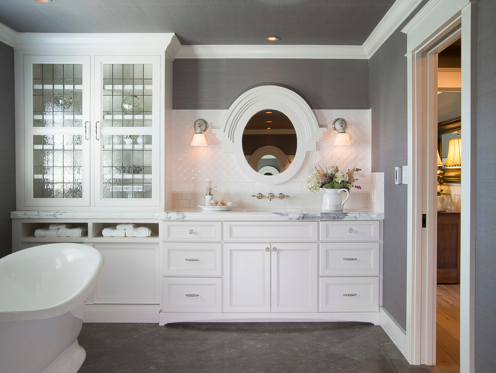 Mid-sized transitional master bathroom in St Louis with recessed-panel cabinets, white cabinets, a freestanding tub, gray tile, subway tile, grey walls, porcelain floors, an undermount sink and marble benchtops.
