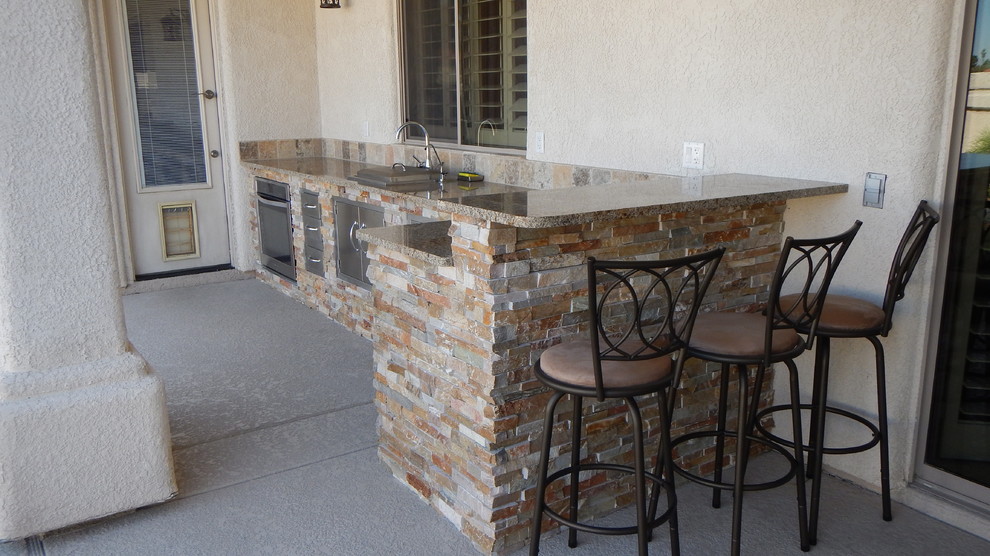 Mid-sized l-shaped home bar in Phoenix with granite benchtops, multi-coloured splashback, stone tile splashback and concrete floors.