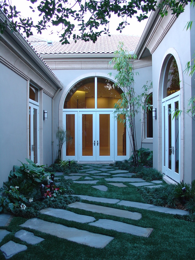 This is an example of a mid-sized traditional front yard shaded garden in Miami with a garden path and natural stone pavers.