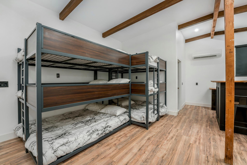 This is an example of a small modern guest bedroom in Los Angeles with white walls, concrete flooring, beige floors and exposed beams.