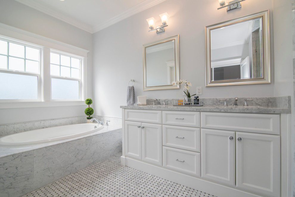 Design ideas for a large traditional master bathroom in Los Angeles with recessed-panel cabinets, white cabinets, a drop-in tub, gray tile, white tile, marble, grey walls, marble floors, an undermount sink and marble benchtops.