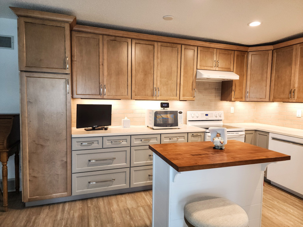 Mid-sized transitional l-shaped vinyl floor and multicolored floor eat-in kitchen photo with an undermount sink, shaker cabinets, solid surface countertops, beige backsplash, subway tile backsplash, white appliances, an island and white countertops