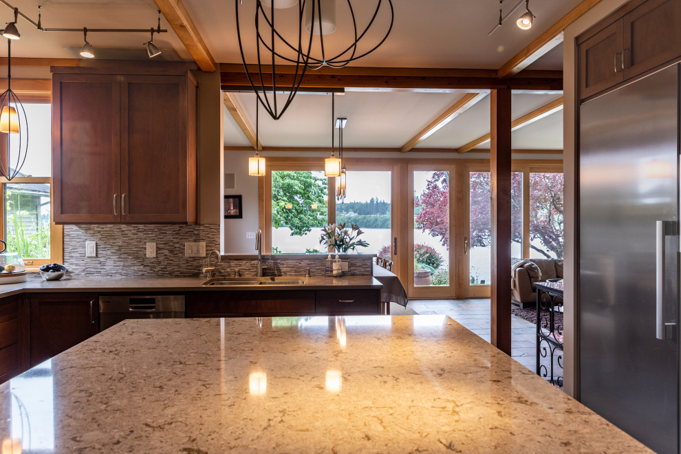 Photo of a mid-sized transitional l-shaped eat-in kitchen in Seattle with an undermount sink, recessed-panel cabinets, light wood cabinets, quartz benchtops, beige splashback, stone tile splashback, stainless steel appliances, slate floors, with island, grey floor, beige benchtop and exposed beam.