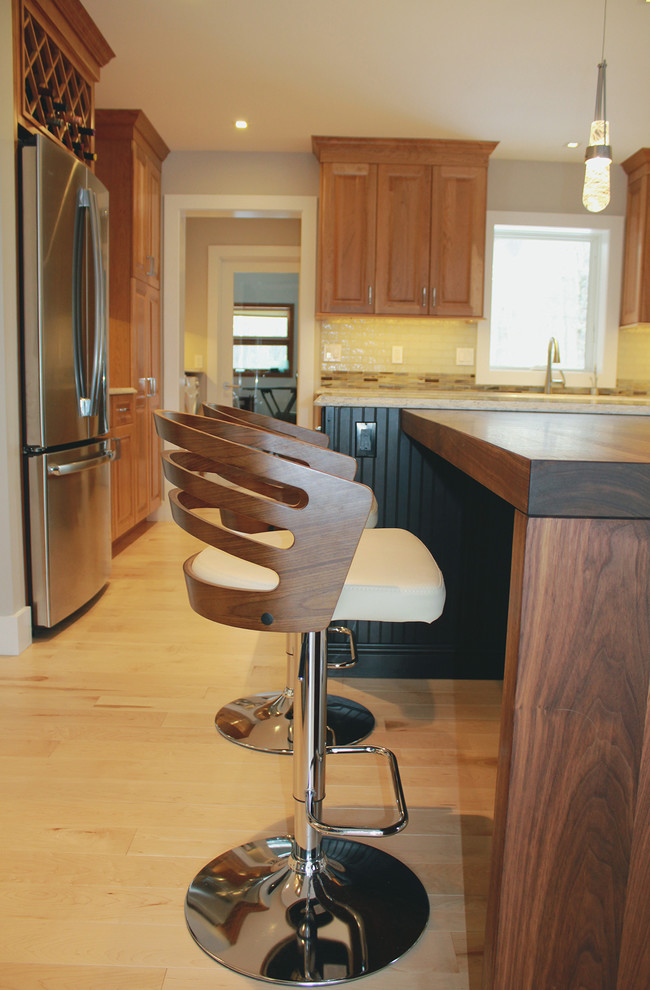 Example of a large transitional u-shaped light wood floor and beige floor open concept kitchen design in Boston with an undermount sink, raised-panel cabinets, medium tone wood cabinets, quartz countertops, multicolored backsplash, glass tile backsplash, stainless steel appliances, an island and beige countertops
