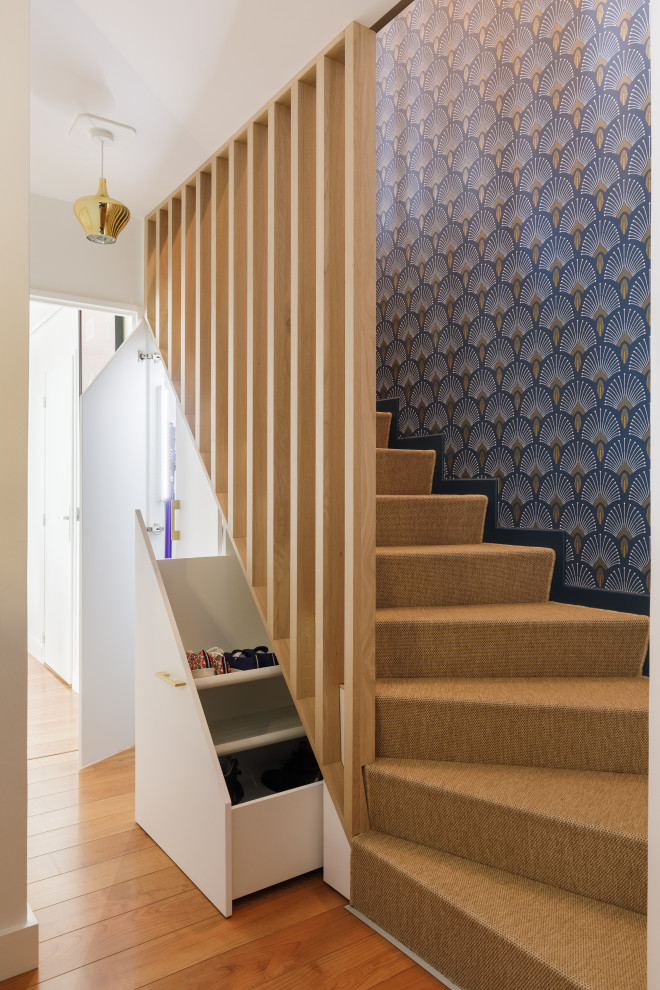 Photo of a mid-sized contemporary carpeted curved staircase in Paris with carpet risers, wood railing and wallpaper.