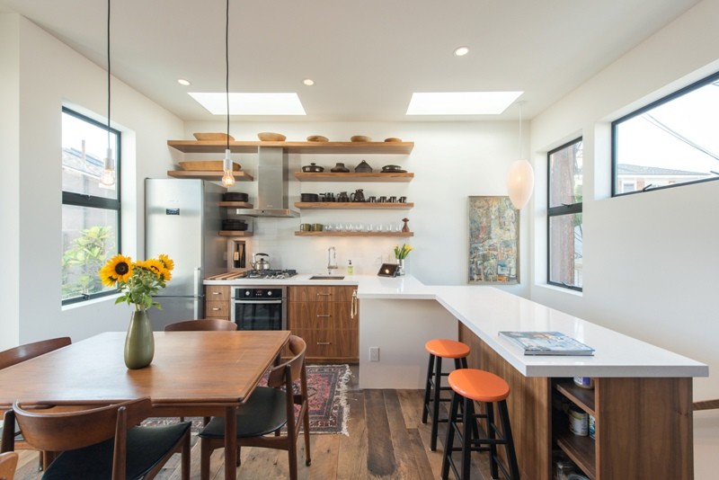 Design ideas for a mid-sized modern single-wall eat-in kitchen in Los Angeles with an undermount sink, flat-panel cabinets, medium wood cabinets, solid surface benchtops, white splashback, subway tile splashback, stainless steel appliances, medium hardwood floors and with island.