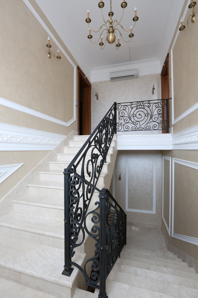 Traditional marble u-shaped staircase in Moscow with marble risers and metal railing.