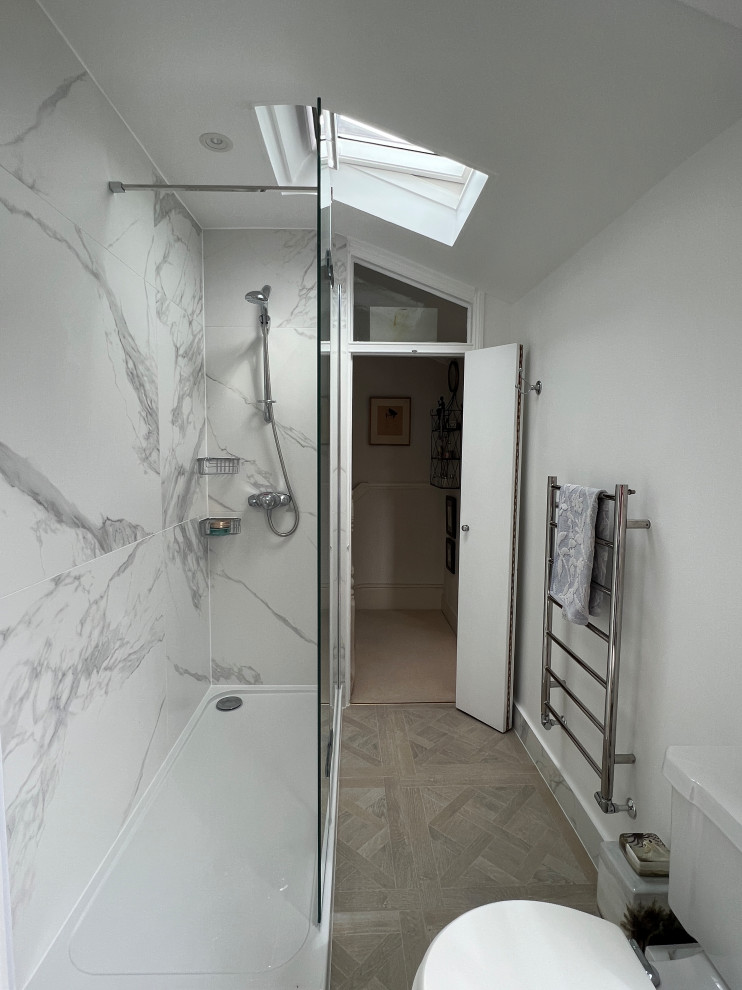 This is an example of a mid-sized traditional master bathroom in London with beaded inset cabinets, grey cabinets, an open shower, a one-piece toilet, white tile, porcelain tile, white walls, porcelain floors, a drop-in sink, brown floor, an open shower, a single vanity and a freestanding vanity.