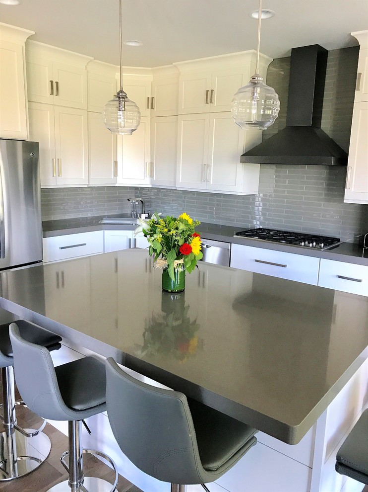 Inspiration for a mid-sized transitional l-shaped light wood floor and gray floor eat-in kitchen remodel with an undermount sink, recessed-panel cabinets, white cabinets, quartz countertops, gray backsplash, ceramic backsplash, stainless steel appliances and an island