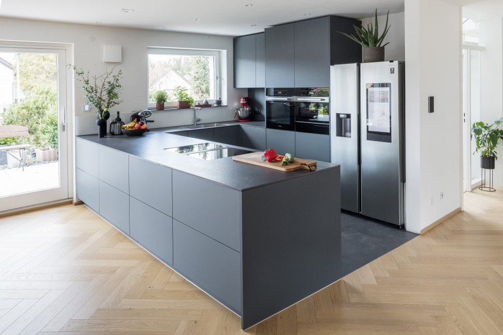 Стильный дизайн: п-образная кухня-гостиная среднего размера в современном стиле с черными фасадами и черной столешницей - последний тренд