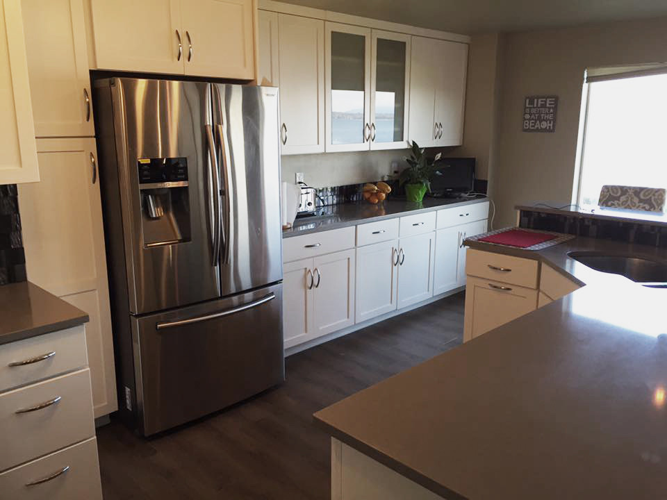 Open concept kitchen - mid-sized transitional l-shaped open concept kitchen idea in Seattle with an undermount sink, shaker cabinets, white cabinets, quartzite countertops, metallic backsplash, glass tile backsplash, stainless steel appliances and an island