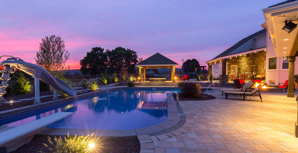 Large contemporary backyard l-shaped lap pool in Other with a water slide and concrete pavers.