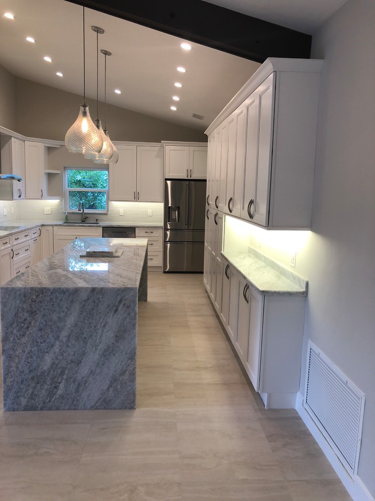 Inspiration for a mid-sized transitional u-shaped beige floor kitchen remodel in Miami with an undermount sink, stainless steel appliances, recessed-panel cabinets, white cabinets, gray backsplash, glass tile backsplash, an island and gray countertops