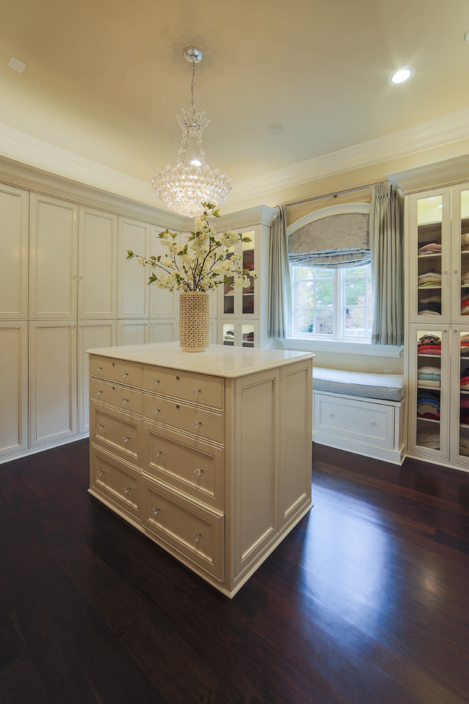 This is an example of a large traditional women's dressing room in Charlotte with recessed-panel cabinets, beige cabinets and dark hardwood floors.