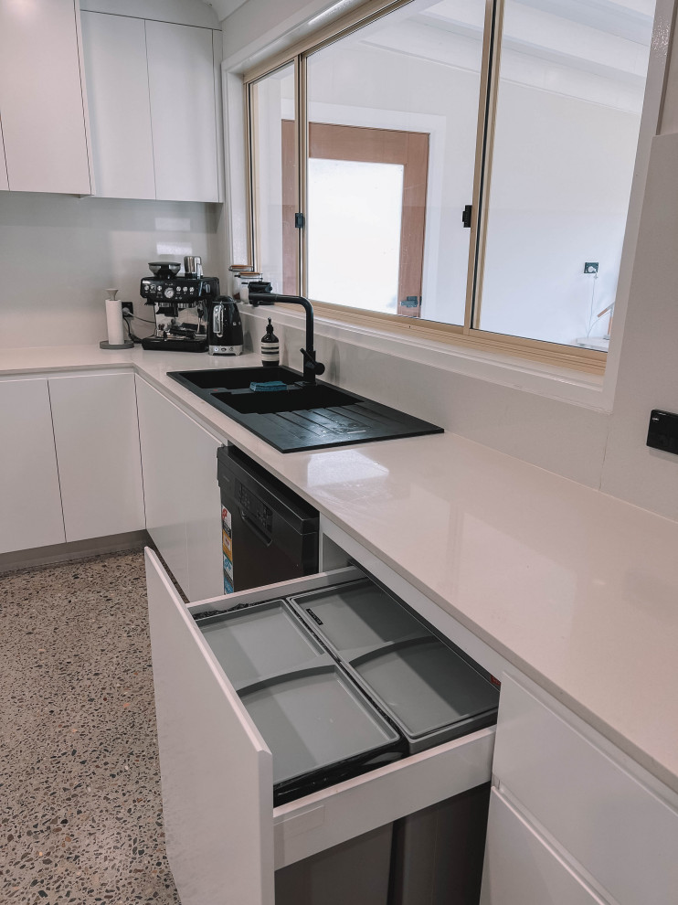 Inspiration for a small scandinavian u-shaped open plan kitchen in Sydney with a double-bowl sink, flat-panel cabinets, white cabinets, quartz benchtops, white splashback, engineered quartz splashback, black appliances, concrete floors, no island, grey floor, white benchtop and timber.