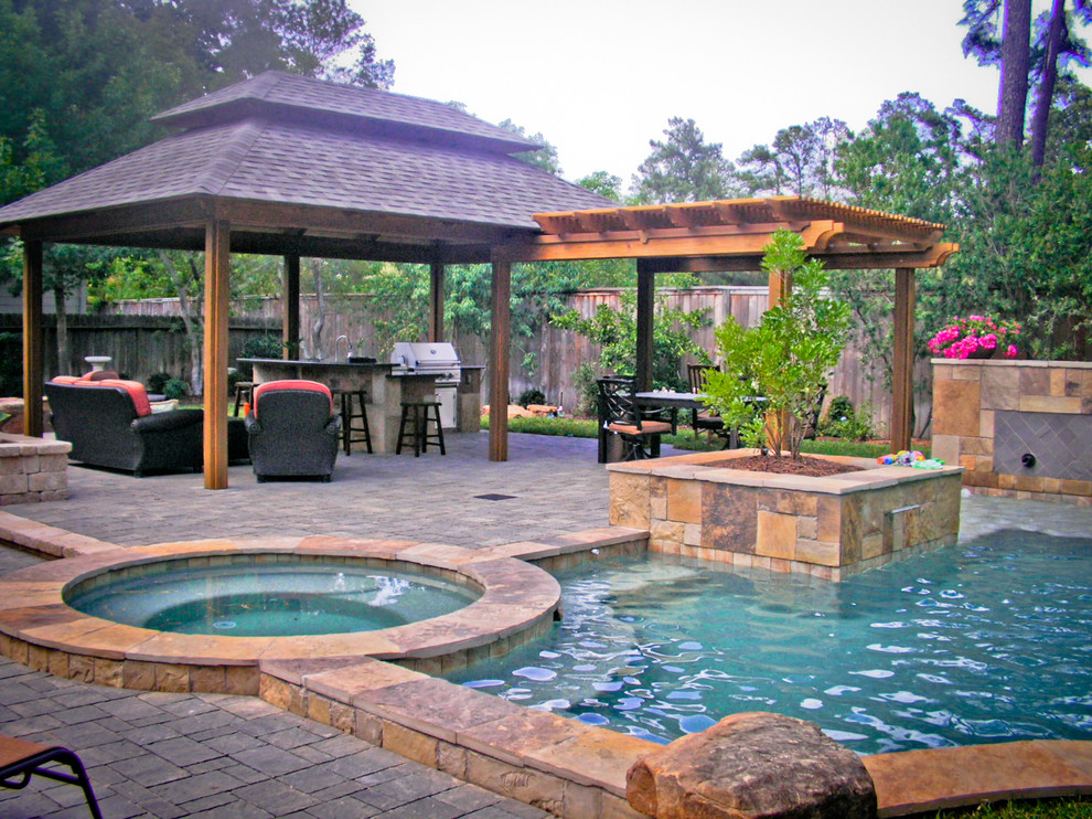 This is an example of a mid-sized mediterranean backyard rectangular natural pool in Houston with a hot tub and natural stone pavers.