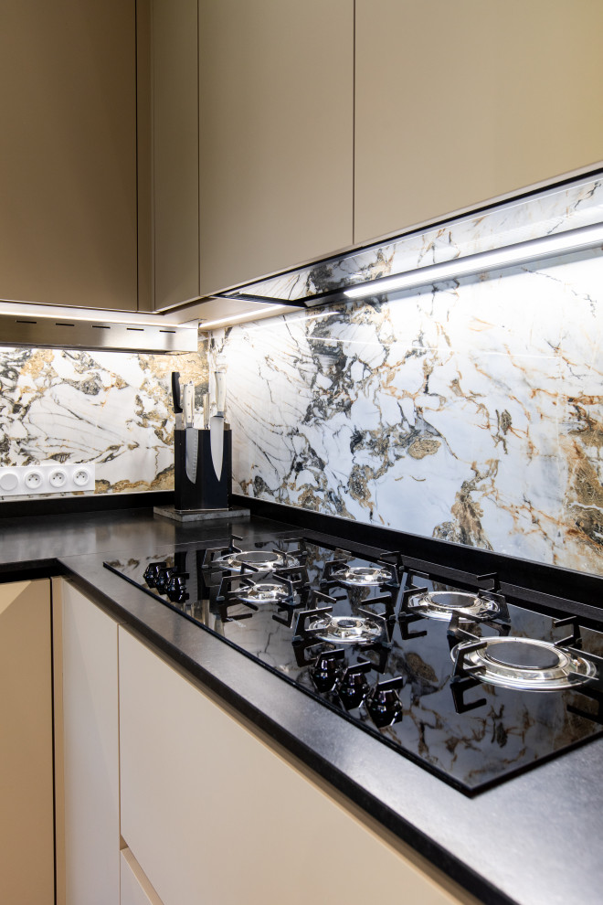 Modern inredning av ett stort svart svart kök, med luckor med profilerade fronter, beige skåp, granitbänkskiva, flerfärgad stänkskydd, stänkskydd i marmor, rostfria vitvaror och en köksö