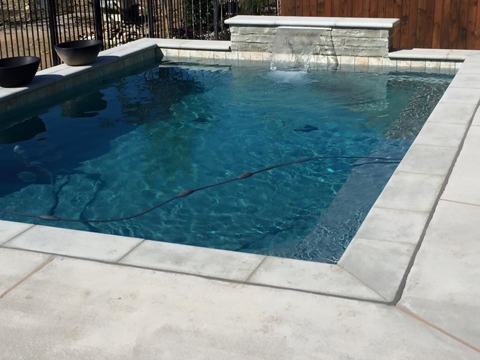 Small contemporary backyard rectangular lap pool in Dallas with a water feature and concrete slab.