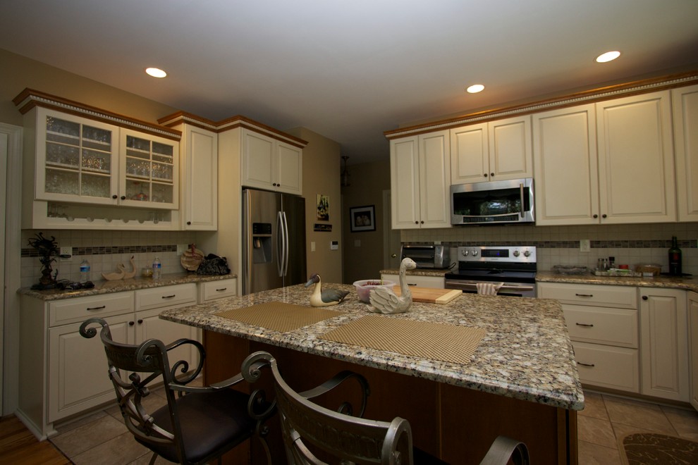 This is an example of a traditional u-shaped eat-in kitchen in Baltimore with raised-panel cabinets, white cabinets, granite benchtops, white splashback, stainless steel appliances and with island.
