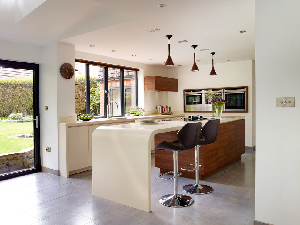 Photo of a mid-sized contemporary l-shaped kitchen in Manchester with an undermount sink, flat-panel cabinets, white cabinets, stainless steel appliances and with island.