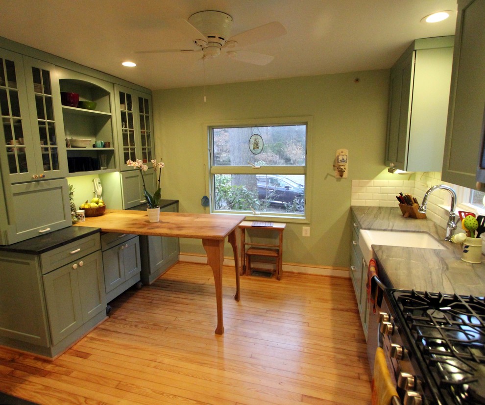 Photo of a small arts and crafts u-shaped separate kitchen in DC Metro with a farmhouse sink, flat-panel cabinets, green cabinets, quartzite benchtops, white splashback, porcelain splashback, stainless steel appliances, light hardwood floors, no island and orange floor.