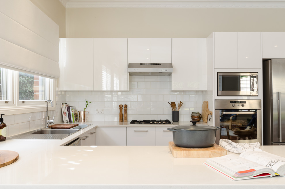 Design ideas for a mid-sized contemporary u-shaped eat-in kitchen in Sydney with a double-bowl sink, flat-panel cabinets, white cabinets, granite benchtops, white splashback, ceramic splashback, stainless steel appliances, dark hardwood floors and with island.