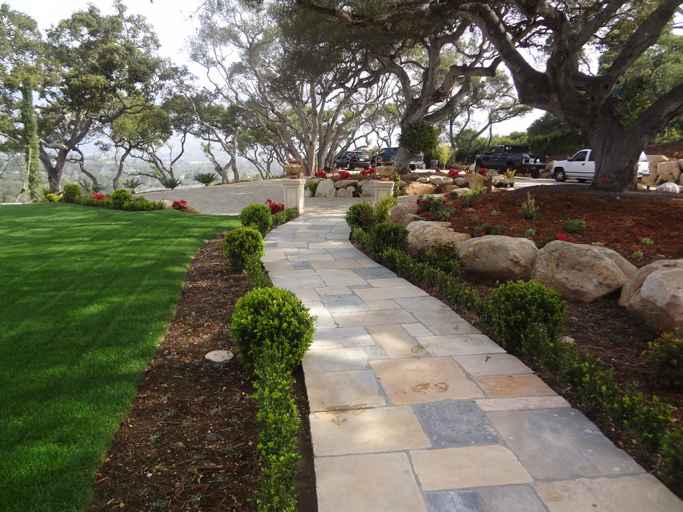 Photo of a large mediterranean front yard patio in Santa Barbara with natural stone pavers.
