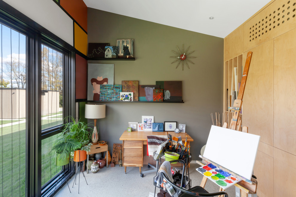 Modelo de estudio abovedado y blanco minimalista pequeño con paredes verdes, suelo de cemento, escritorio independiente y suelo gris