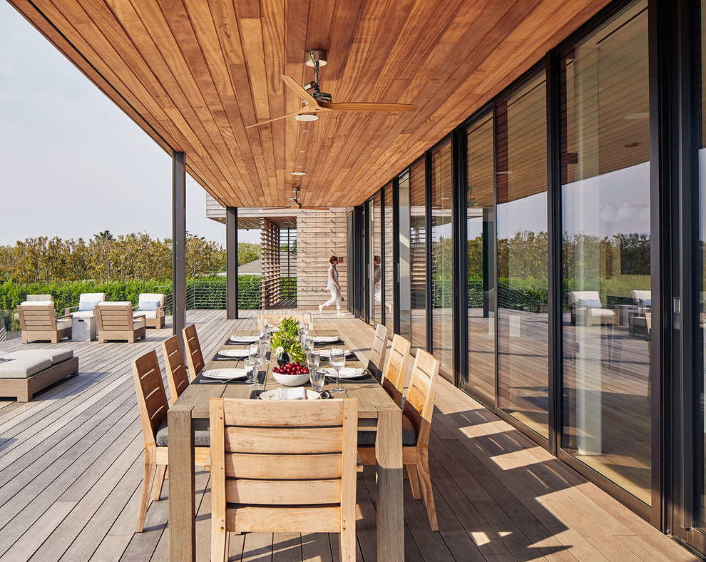 This is an example of an expansive beach style deck in New York with a roof extension.