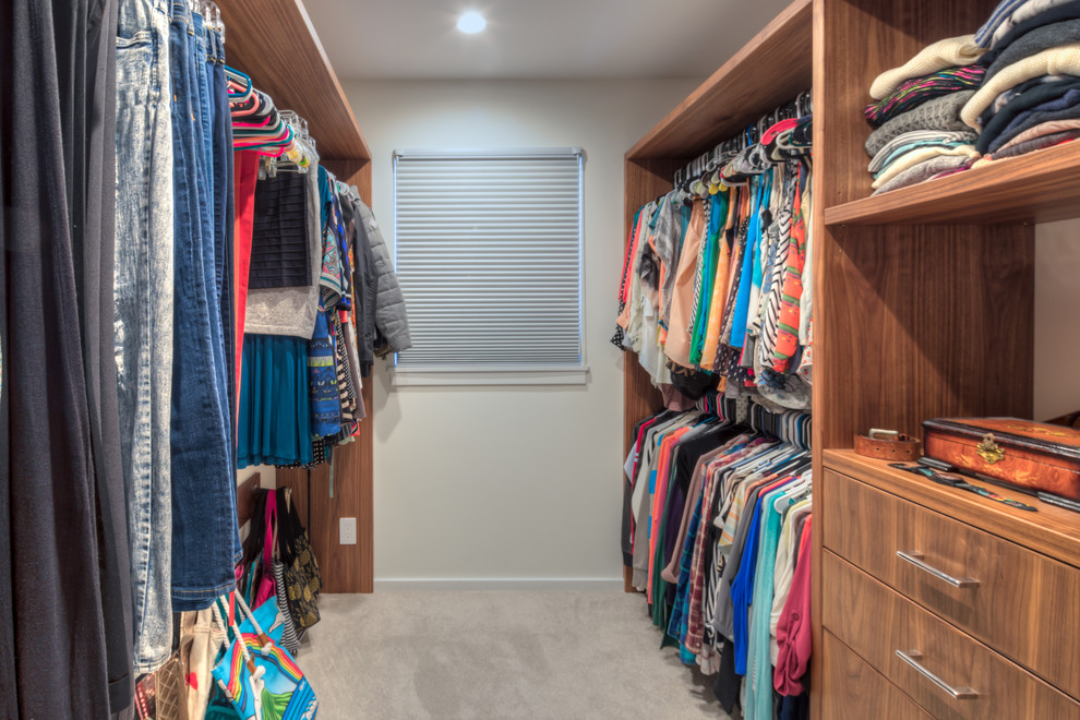 Inspiration for a mid-sized contemporary gender-neutral walk-in wardrobe in Hawaii with open cabinets, medium wood cabinets, carpet and beige floor.