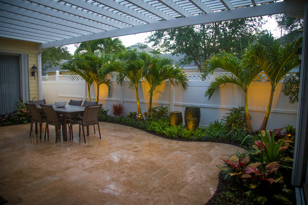Small tropical courtyard patio in Miami with a water feature, natural stone pavers and a pergola.