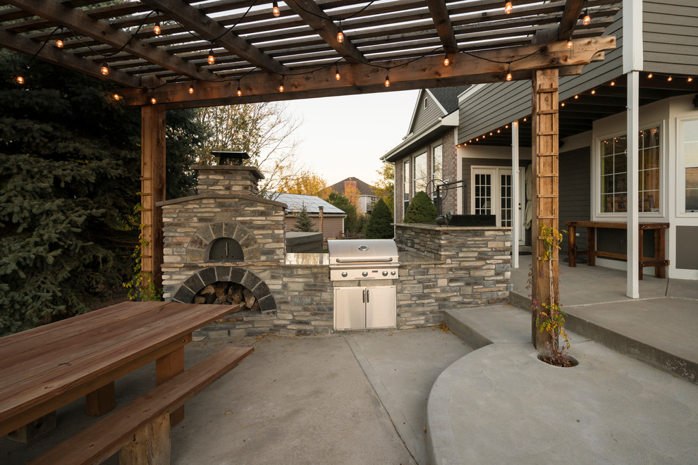 This is an example of a traditional backyard patio in Denver with an outdoor kitchen, concrete slab and a pergola.