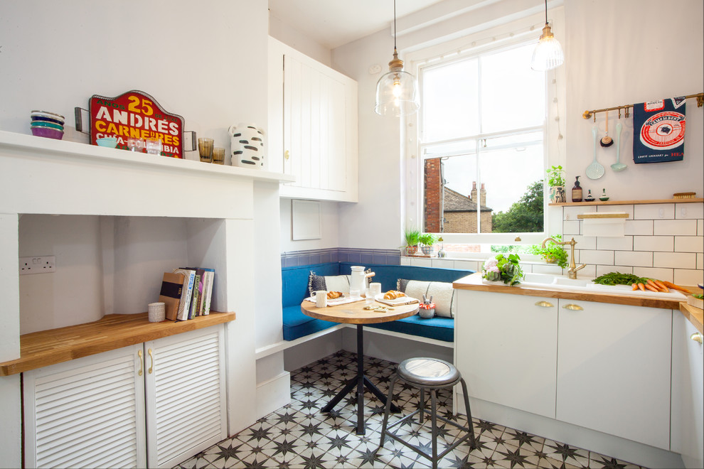 Design ideas for a small eclectic l-shaped kitchen in London with flat-panel cabinets, white cabinets, a drop-in sink, white splashback, subway tile splashback, no island and multi-coloured floor.