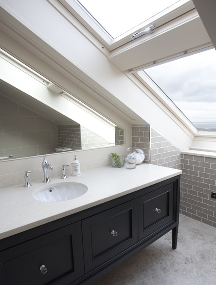 This is an example of a traditional bathroom in Dublin with an undermount sink, black cabinets, gray tile, subway tile, limestone floors, engineered quartz benchtops and recessed-panel cabinets.