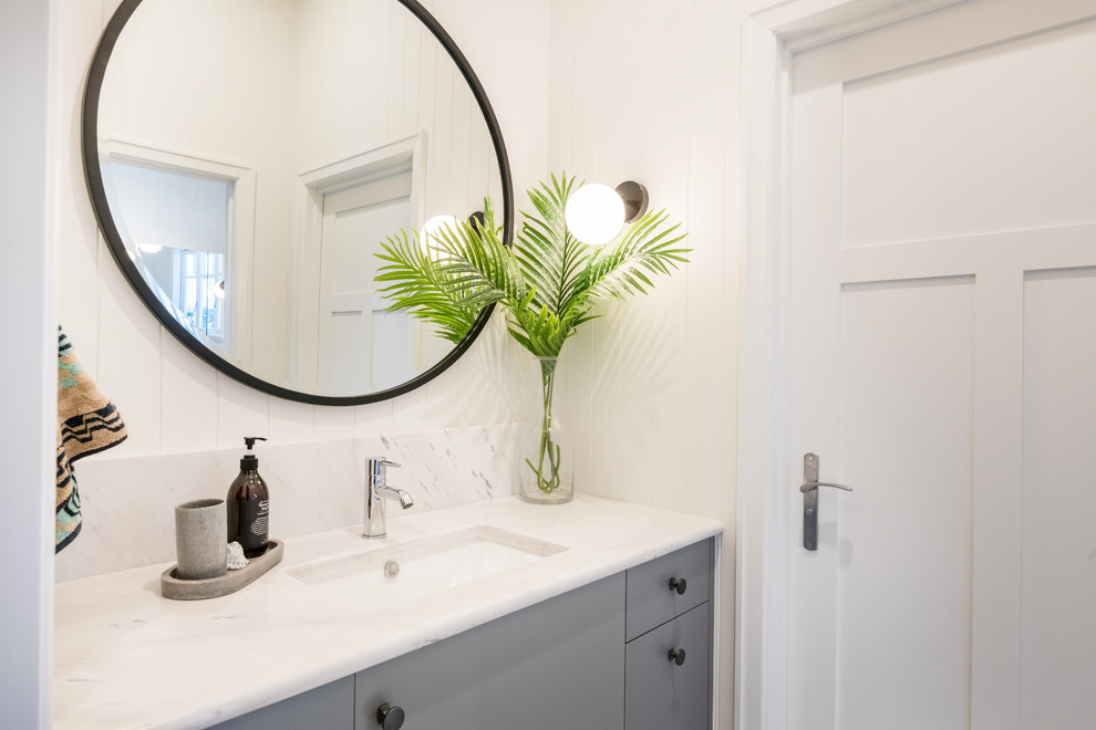 Photo of a small traditional powder room in Brisbane with white walls, marble floors, an undermount sink, marble benchtops, grey floor and white benchtops.