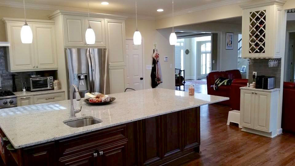 Example of a large transitional l-shaped dark wood floor and brown floor eat-in kitchen design in Miami with a farmhouse sink, raised-panel cabinets, white cabinets, gray backsplash, subway tile backsplash, stainless steel appliances and an island