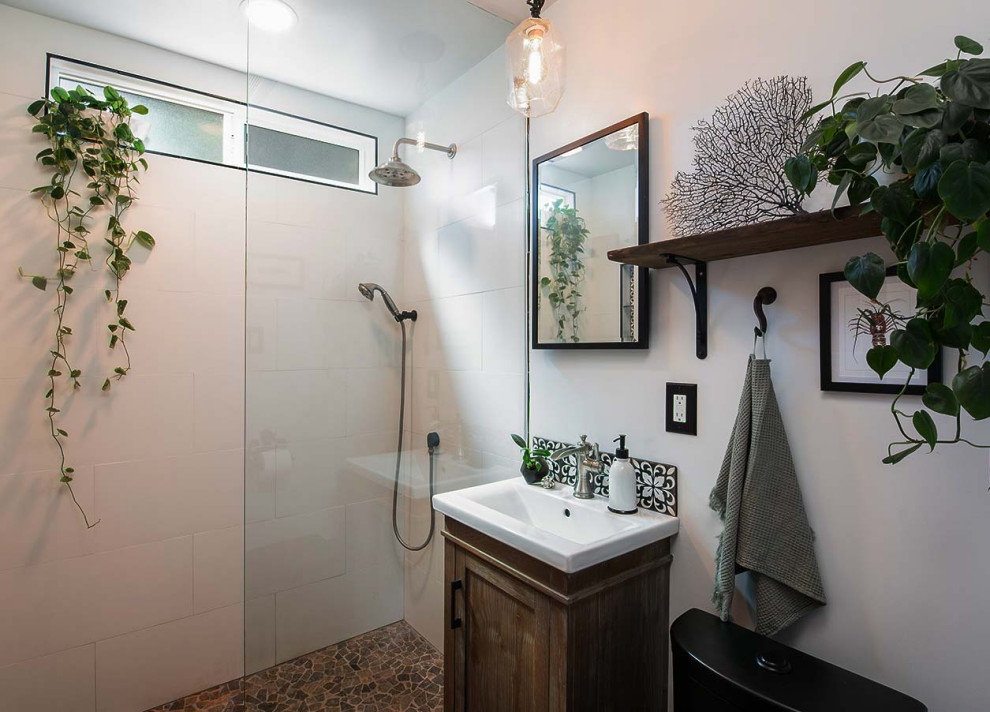 Photo of a medium sized nautical bathroom in Los Angeles with shaker cabinets, distressed cabinets, a built-in shower, a one-piece toilet, black and white tiles, porcelain tiles, white walls, pebble tile flooring, a pedestal sink, solid surface worktops, grey floors, an open shower, white worktops, a wall niche, a single sink and a freestanding vanity unit.