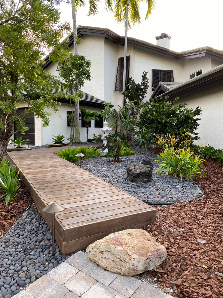 This is an example of a mid-sized asian full sun front yard river rock formal garden in Miami.